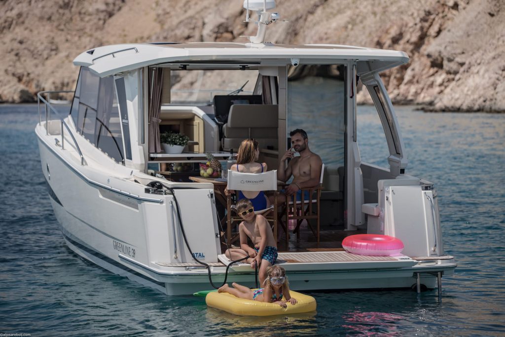 Family enjoying the Greenline 39 cockpit and swim platform with children in the water