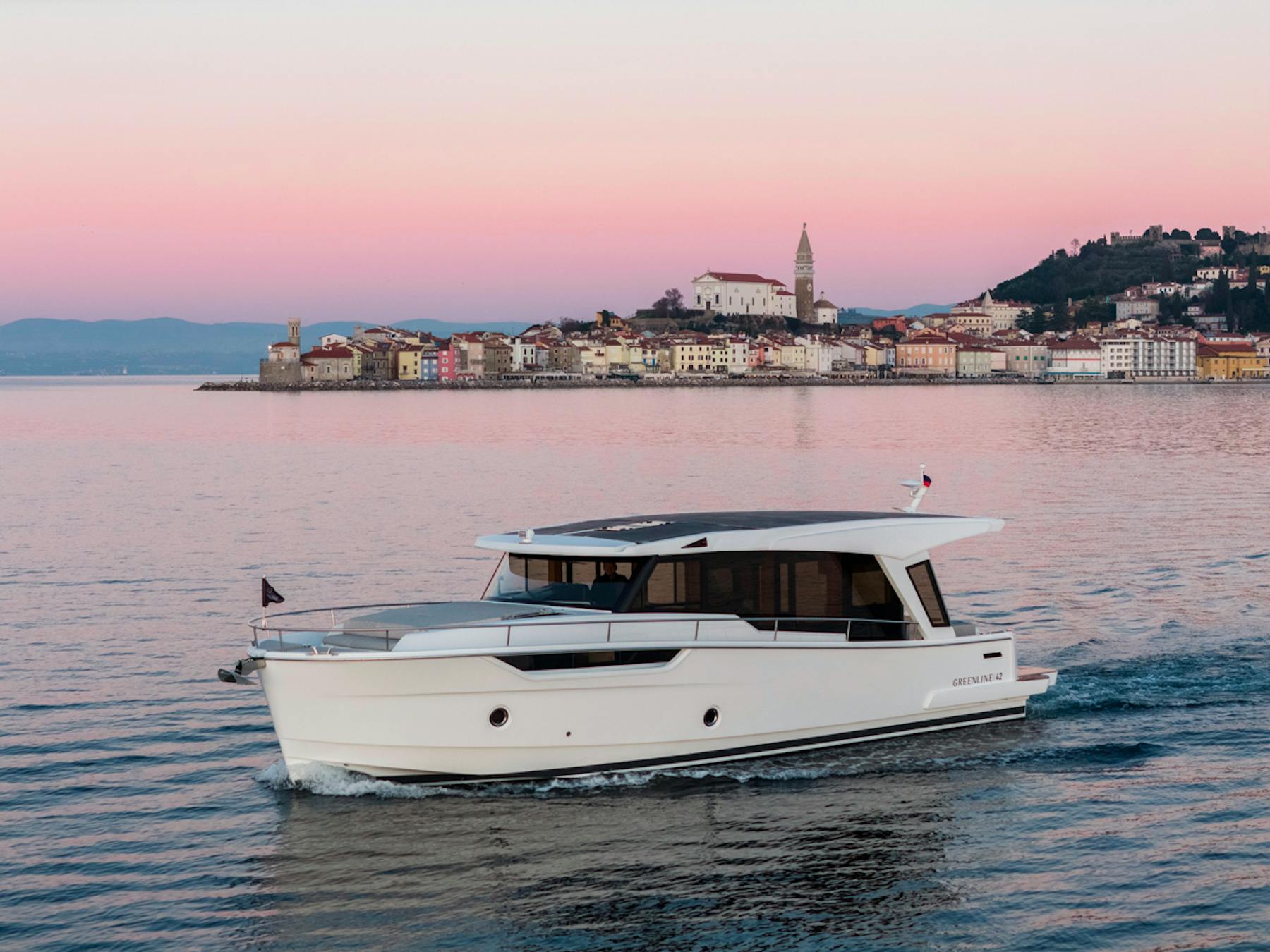 Greenline 42 cruising past a coastal town at dusk